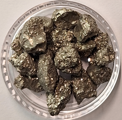 Pyrit (Eisenkies) ist ein goldfarbenes Mineral, bekannt als "Katzengold" oder "Narrengold", weil es oft mit Gold verwechselt wird. Sein Name leitet sich vom griechischen Wort für "Feuer" (pyr) ab, da es Funken schlägt, wenn es gegen Eisen geschlagen wird, und so früher zur Feuermacherei genutzt wurde. Es steht symbolisch für Schutz, Mut, innere Stärke, Selbstbewusstsein und Tatkraft, wird in der Schmuckherstellung verwendet und gilt als Energiebringer. 